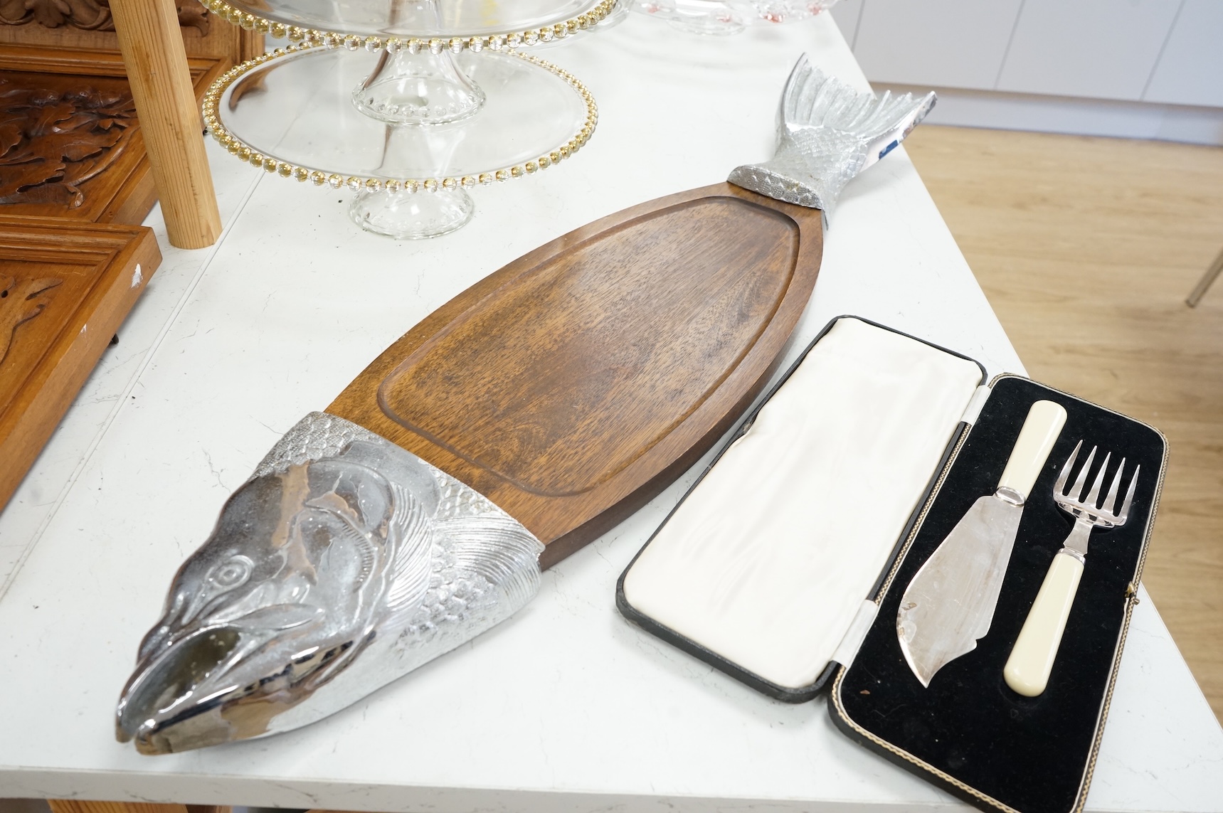 A wooden 'Fish' serving platter with plated mounts and a pair of servers, platter 87cm long